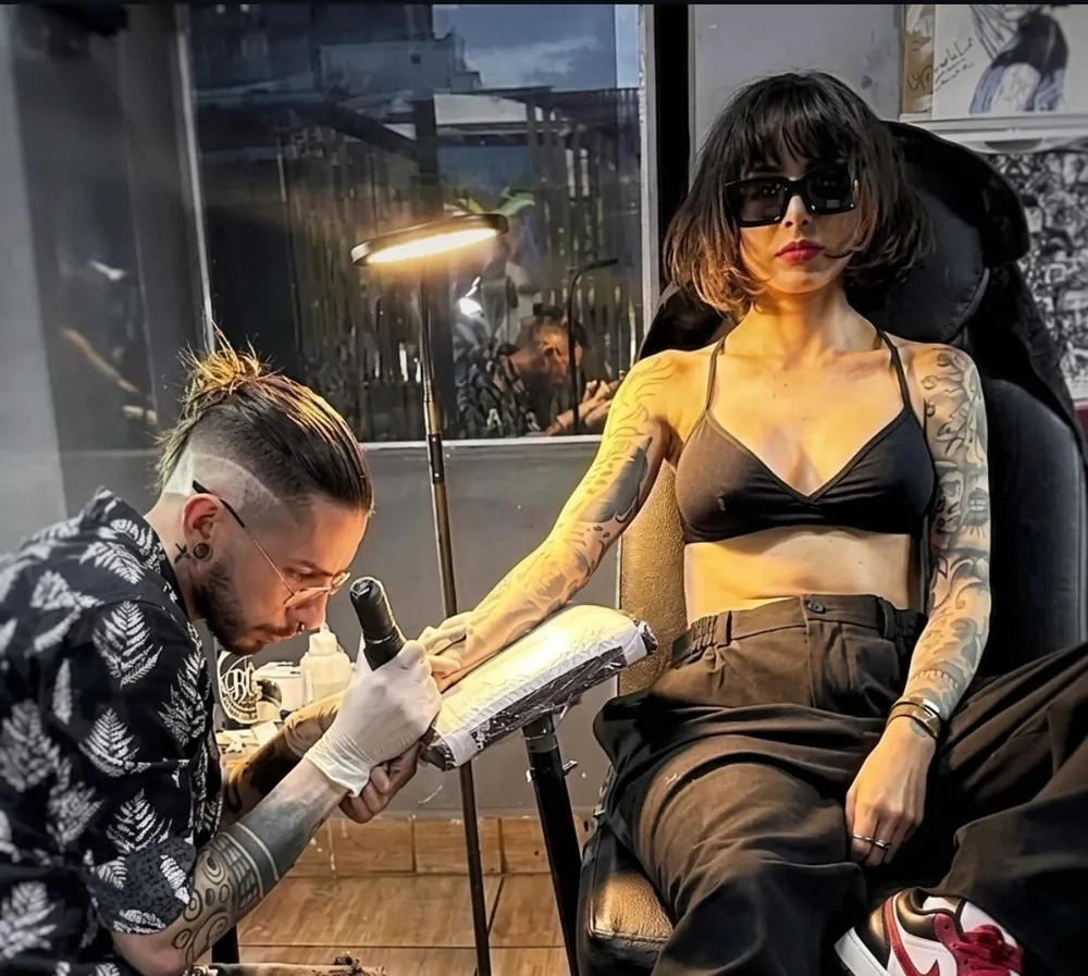 Javier Camargo tatuando el antebrazo de una clienta durante una sesión